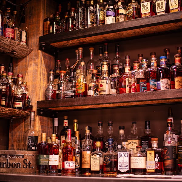 A well-stocked bar with numerous bottles of bourbon and whiskey on wooden shelves.